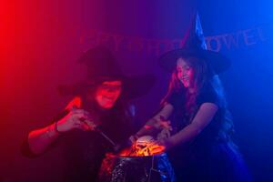 deux Halloween sorcières fabrication une potion et conjurer dans Halloween nuit. la magie, vacances et mystique concept. photo