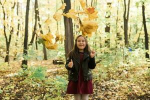 asiatique enfant fille en riant et en jouant dans le l'automne sur le la nature marcher en plein air photo
