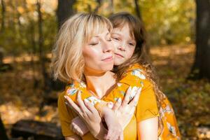 Jeune mère avec sa peu fille dans un l'automne parc. tomber saison, parentalité et les enfants concept. photo