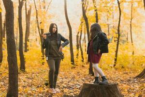 mère prise image sa charismatique fille sur rétro caméra dans l'automne parc. loisirs et loisir concept. photo