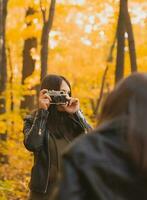 mère prise image sa charismatique fille sur rétro caméra dans l'automne parc. loisirs et loisir concept. photo