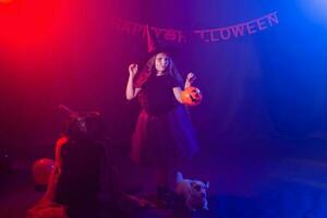 marrant enfant fille dans sorcière costume pour Halloween avec citrouille jack et chien. photo