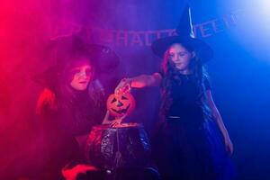 marrant enfant fille et femme dans sorcières costumes pour Halloween avec citrouille jack. photo