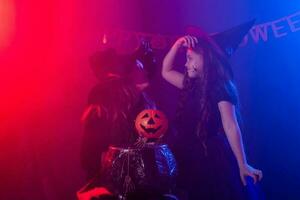 marrant enfant fille et femme dans sorcières costumes pour Halloween avec citrouille jack photo