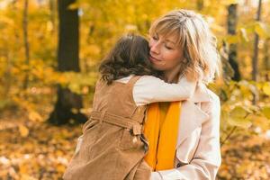 mère avec enfant dans sa bras contre Contexte de l'automne la nature. famille et saison concept. photo