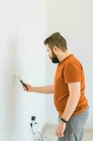homme lisse mur surface avec une mur broyeur. Masculin moudre une blanc plâtre mur - rénovation et redécoration concept photo