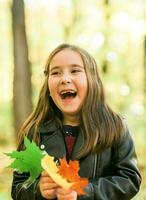 l'automne émotif portrait de en riant enfant en marchant dans parc ou forêt photo