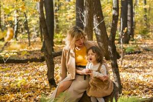 mère réconfortant sa pleurs peu fille dans l'automne la nature. émotions et famille concept. photo