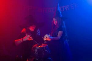 deux Halloween sorcières fabrication une potion et conjurer dans Halloween nuit. la magie, vacances et mystique concept. photo
