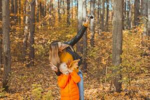 fils et mère sont prise selfie sur caméra dans l'automne parc. Célibataire parent, loisir et tomber saison concept. photo