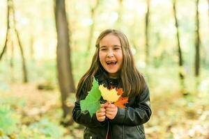 l'automne émotif portrait de en riant enfant en marchant dans parc ou forêt photo