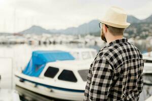 arrière vue homme portant chapeau avec yachts et Marina Contexte avec copie espace et vide endroit pour La publicité photo