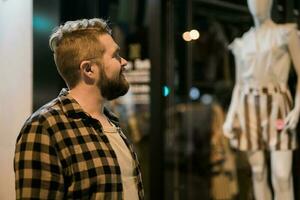 homme à la recherche à magasin fenêtre dans soir rue - boutique et Shopaholic consumérisme concept photo