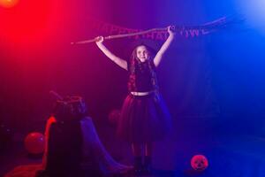 marrant enfant fille dans sorcière costume pour Halloween avec citrouille jack et balai. photo