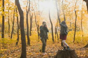 mère photographe prend des photos de une sa fille dans le parc dans l'automne. loisirs, photo art et loisir concept.