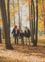 grand-mère et mère avec petite fille des promenades ensemble dans l'automne parc et ayant amusement. génération, loisir et famille concept. photo