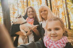 mère, grand-mère et peu petite fille avec jack Russell terrier chien prise selfie par téléphone intelligent en plein air dans l'automne la nature. famille, animaux domestiques et génération concept photo