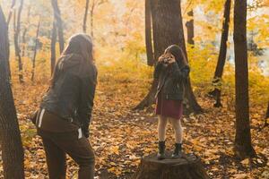 enfant prise image sa mère sur rétro caméra dans l'automne parc. loisirs et loisir concept. photo