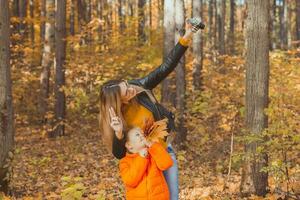 fils et mère sont prise selfie sur caméra dans l'automne parc. Célibataire parent, loisir et tomber saison concept. photo