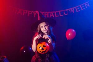 marrant enfant fille dans sorcière costume pour Halloween avec citrouille jack. photo