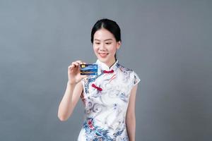 une femme asiatique porte une robe traditionnelle chinoise avec une main tenant une carte de crédit photo