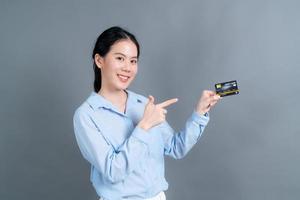 portrait d'une jolie jeune femme asiatique montrant une carte de crédit photo