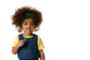 une peu mignonne africain américain fille brossage sa dents, isolé plus de blanc Contexte avec espace de copie. en bonne santé les dents concept. photo