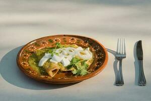 saveur le authentique mexicain saveur de vert enchiladas servi sur une assiette avec argenterie photo