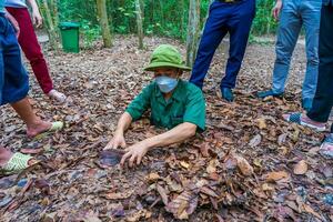 cu chi, viet nam - 20 mai 2023 le cu chi tunnels. une guider démontrant Comment une vietcong cacher dans le tunnel. c'est utilisé dans vietnam guerre. célèbre touristique attraction dans vietnam. Stock photo