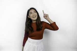 excité asiatique femme portant rouge T-shirt, montrer du doigt à le copie espace sur Haut de son, isolé par blanc Contexte photo