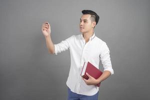 portrait, de, homme, étudiant universitaire, tenue, livre, dans, studio, fond gris photo