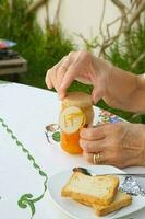 un vieux femme est ouverture une verre de confiture. photo