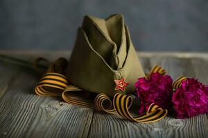 militaire casquette, œillets, Saint George ruban sur une en bois surface. photo