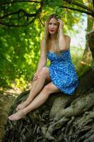 femme dans une bleu robe sur une arbre racine photo