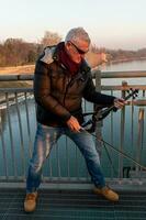 attrayant milieu vieilli musicien homme en jouant un électrique violon en plein air photo