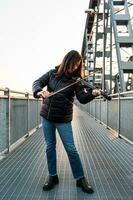 attrayant milieu vieilli femme en jouant un électrique violon en plein air photo