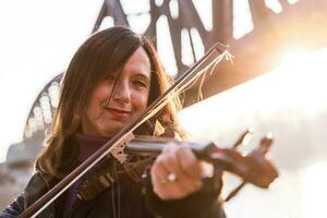 attrayant milieu vieilli femme en jouant un électrique violon en plein air photo