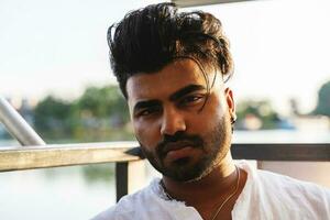 portrait de Jeune Beau pakistanais homme séance sur bateau voile pendant été vacances photo