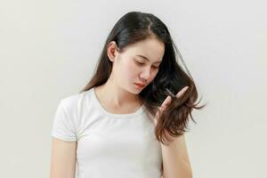 asiatique femmes sont inquiet à propos leur endommagé cheveux provoquant une manquer de de confiance. cheveux perte traitement concept, endommagé cheveux, beauté salon. photo