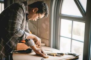 asiatique Charpentier travail avec équipement outils sur en bois table dans charpenterie magasin. concept travail de menuisier. professionnel travail en bois homme. photo