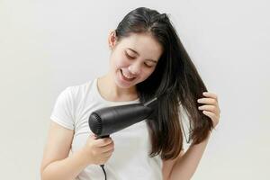 content asiatique Jeune femme séchage cheveux sur blanc arrière-plan, traitement cheveux concept, endommagé cheveux, beauté salon. photo