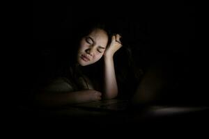 Jeune asiatique femmes travail en retard à nuit stressé dehors. fatigué et épuisé de travail sur ordinateur portable dans le chambre à coucher. photo