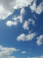 nuages blancs dans le ciel bleu. beau fond bleu clair. peu nuageux, beau temps. nuages bouclés par une journée ensoleillée. photo