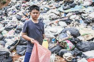 une pauvres garçon collecte des ordures déchets de une décharge site dans le faubourgs . les enfants travail à ces des sites à gagner leur moyens de subsistance. la pauvreté concept. photo