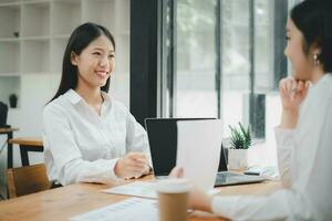 deux femmes analysant des documents assises sur une table au bureau. femmes cadres au travail au bureau discutant de certains documents. photo