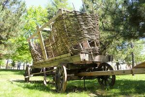 un vieux en bois Chariot avec grand roues dans le ferme avec forêt Contexte photo