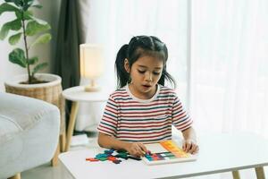 peu asiatique fille en jouant avec coloré en bois blocs à maison. éducation concept. photo