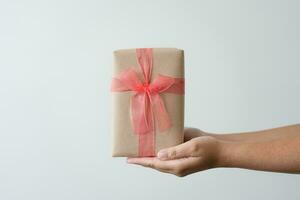 femme porter cadeau papier boîte attacher mignonne ruban pour spécial occasion. livraison Envoi en cours présent à Quelqu'un spécial à remercier ou surprendre. photo