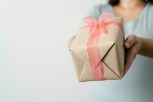 femme porter cadeau papier boîte attacher mignonne ruban pour spécial occasion. livraison Envoi en cours présent à Quelqu'un spécial à remercier ou surprendre. photo