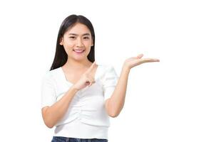 preety asiatique femme dans noir longue cheveux porte blanc chemise des stands souriant et montrer du doigt en haut à présent quelque chose tandis que isolé sur blanc Contexte. photo